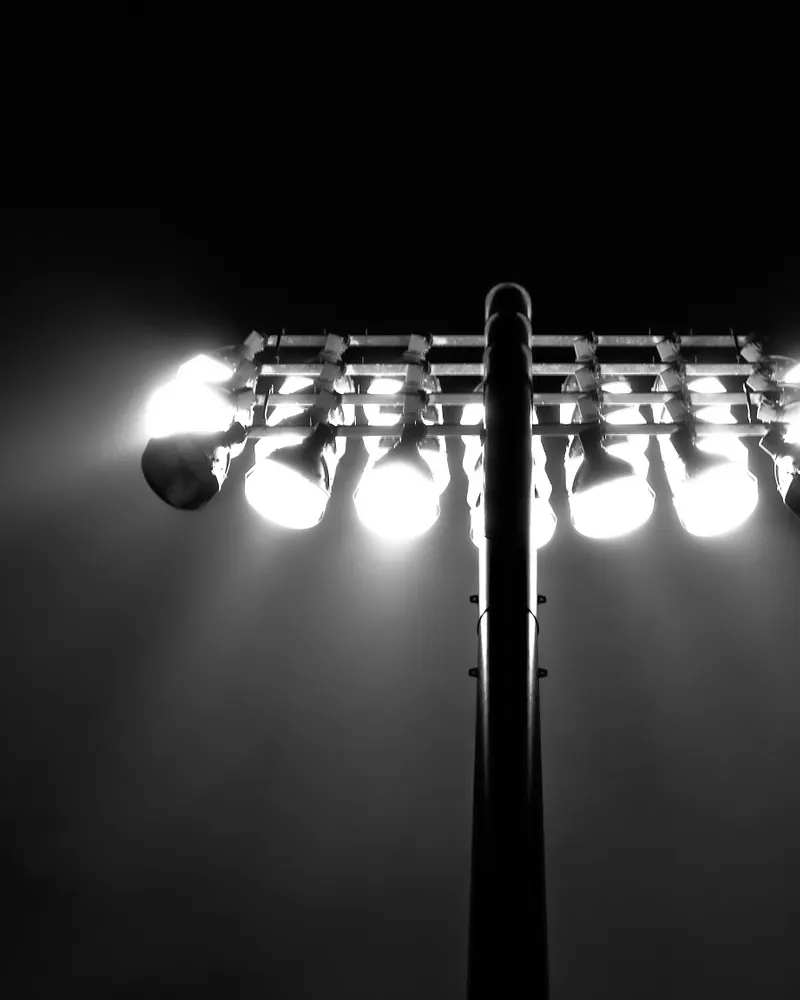 One of the stadium's four original floodlight towers, lamps blazing against a black sky.