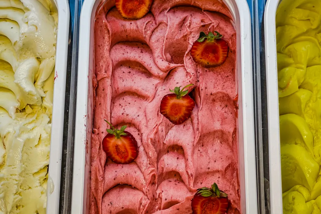 Trays in the case: vanilla, strawberry studded with halved berries, and lemon.
